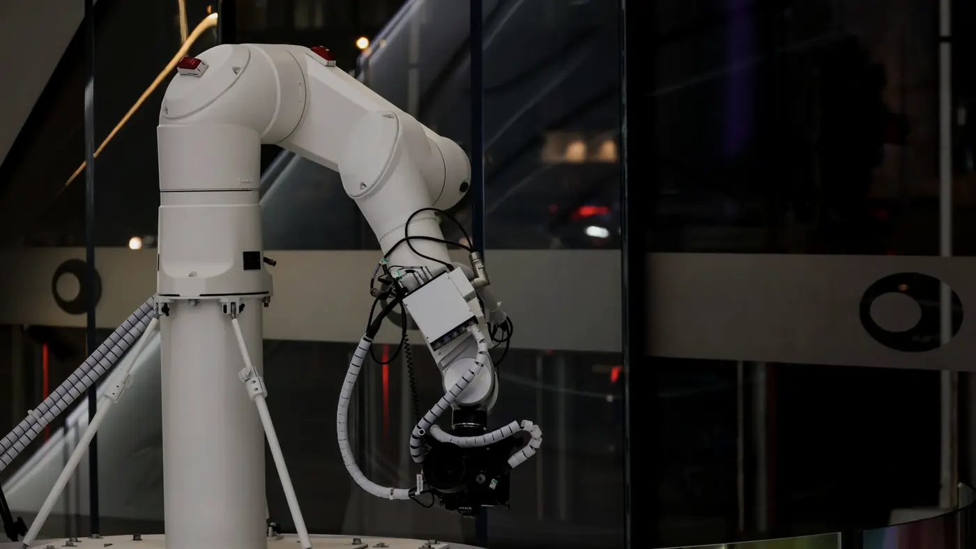 Un bras robotisé blanc en environnement de travail, image de l'automatisation qui remplace des gestes humains.