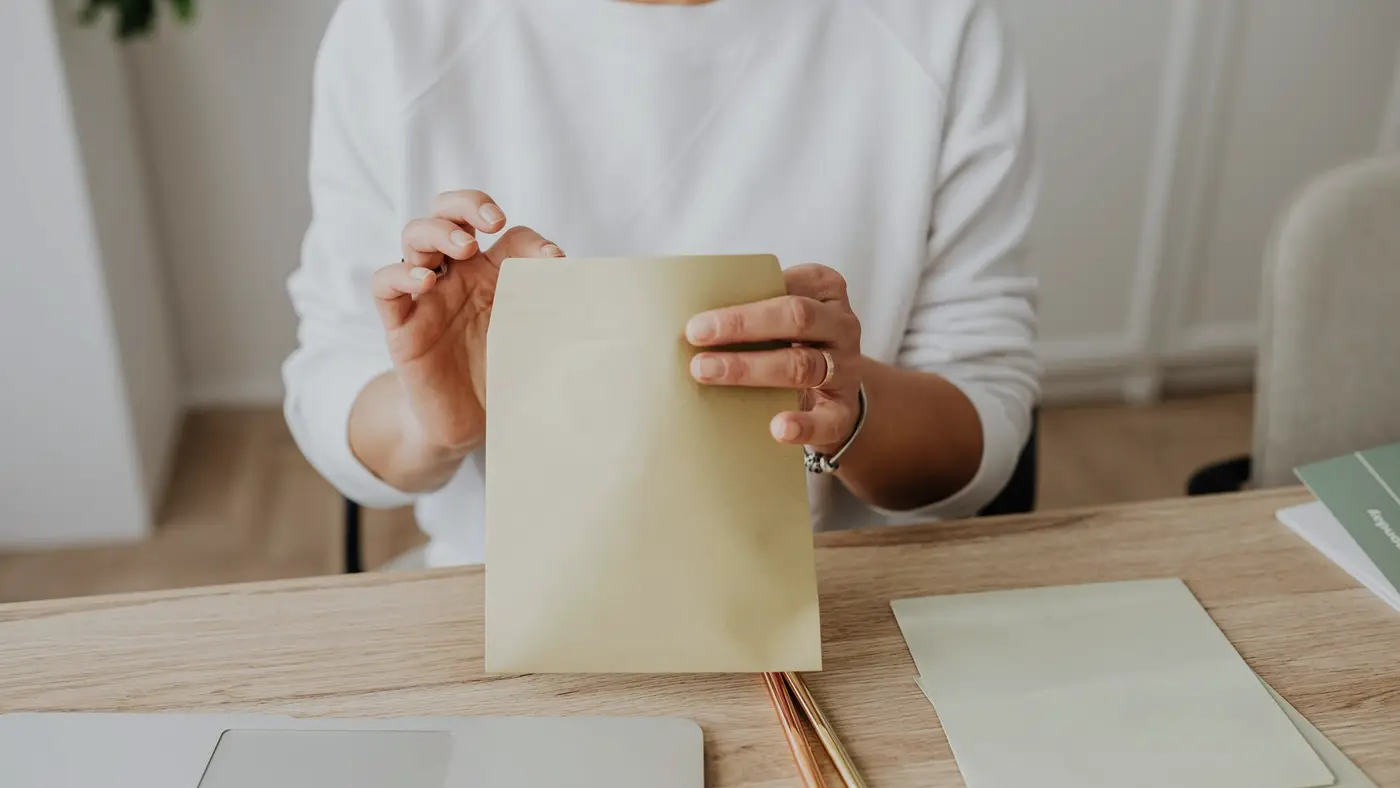 Une personne tient une enveloppe à son bureau : un message peut partir d'une adresse authentique sans que son titulaire l'ait écrit.