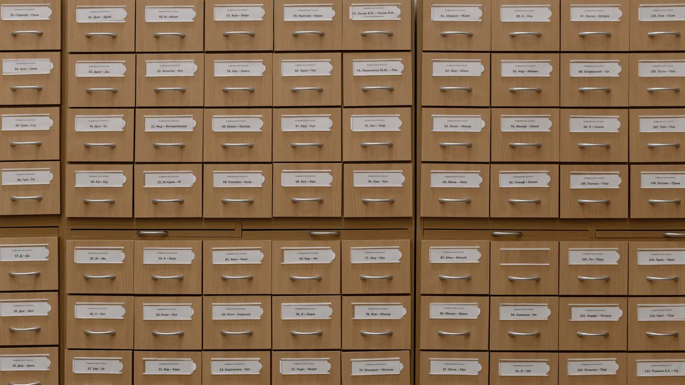 Un mur de tiroirs de fichier aux étiquettes alignées : un catalogue consultable en ligne peut être aspiré en entier sans forcer aucune porte.