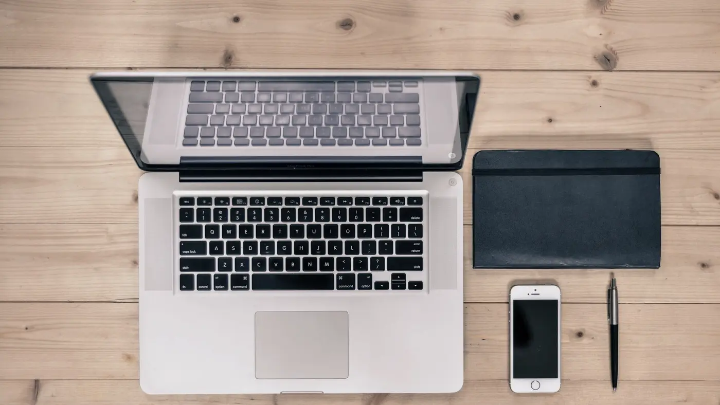 Un clavier et un carnet sur un bureau éclairé de côté, évoquant le travail quotidien avec un assistant conversationnel.