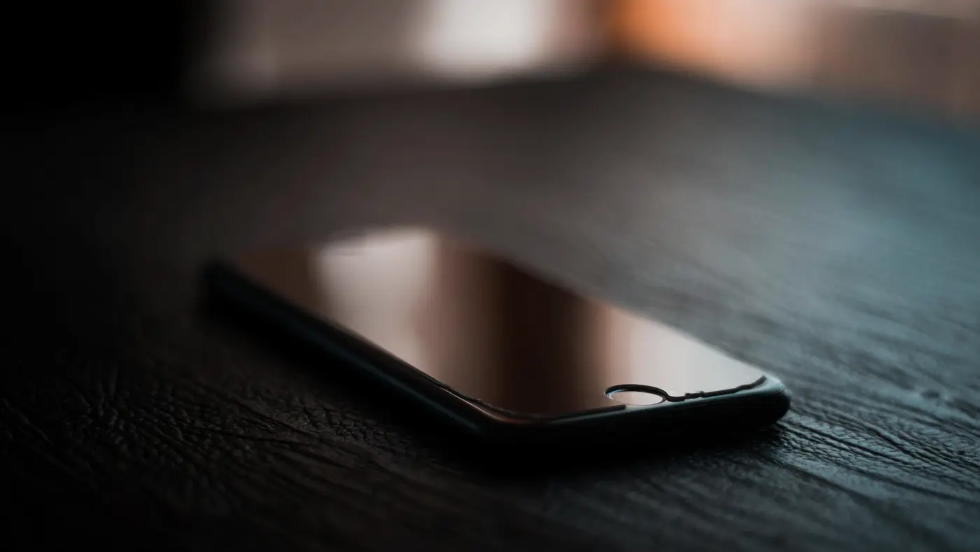 Un smartphone posé sur une table sombre : une clé oubliée dans une application reste lisible par quiconque télécharge son fichier.
