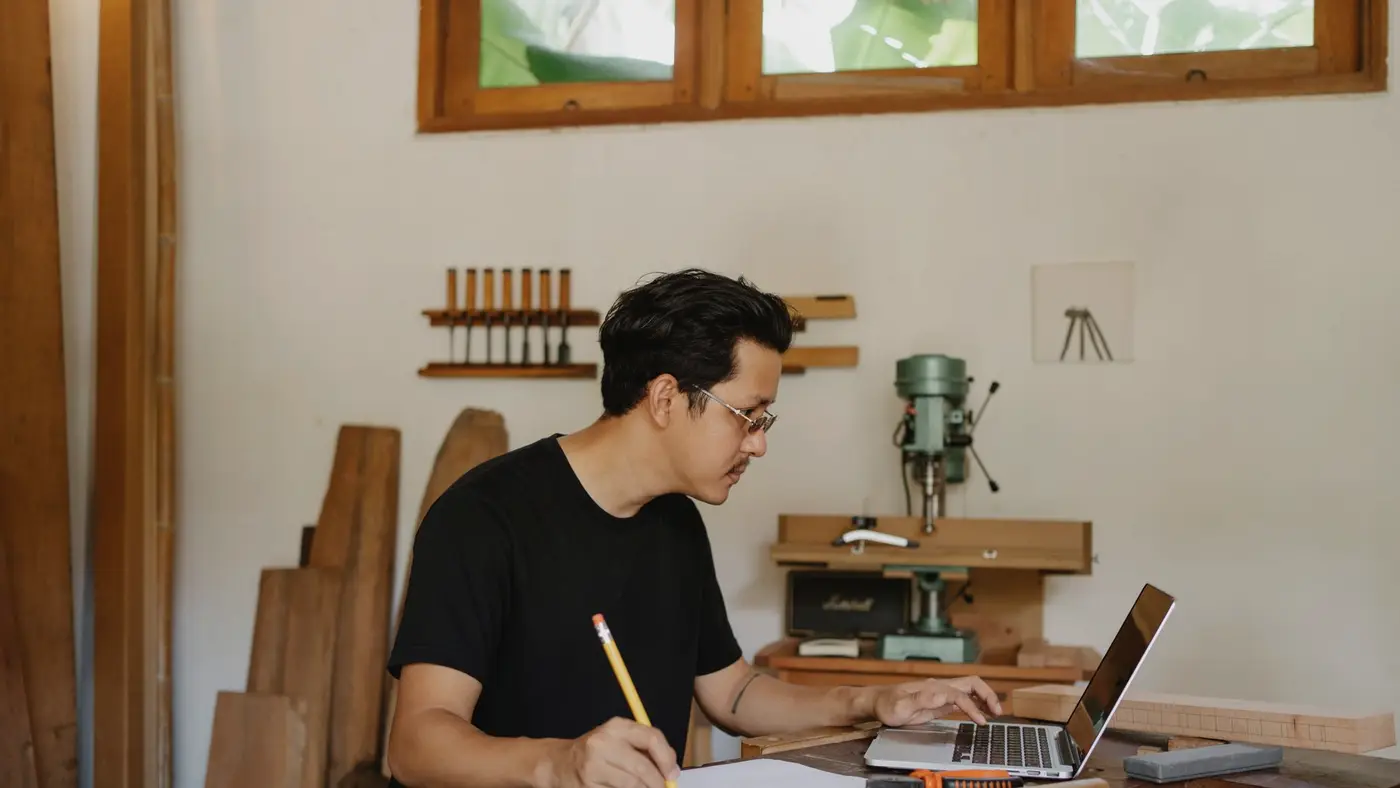 Un ordinateur portable allumé au milieu des outils d'un atelier d'artisan : le message frauduleux arrive là où personne n'est équipé pour le vérifier.