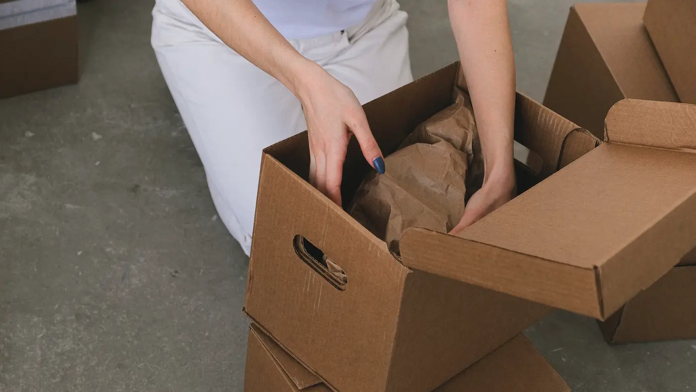 Des mains ouvrent un carton de livraison garni de papier de calage : le détail d’une commande en dit long sur qui l’a passée.