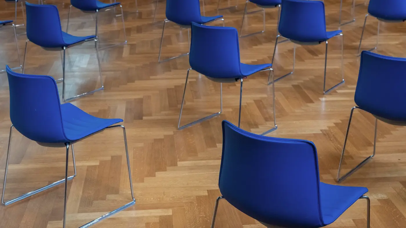 Des chaises bleues espacées dans une salle d’attente vide : un rendez-vous médical laisse une trace administrative, distincte du dossier de soins.