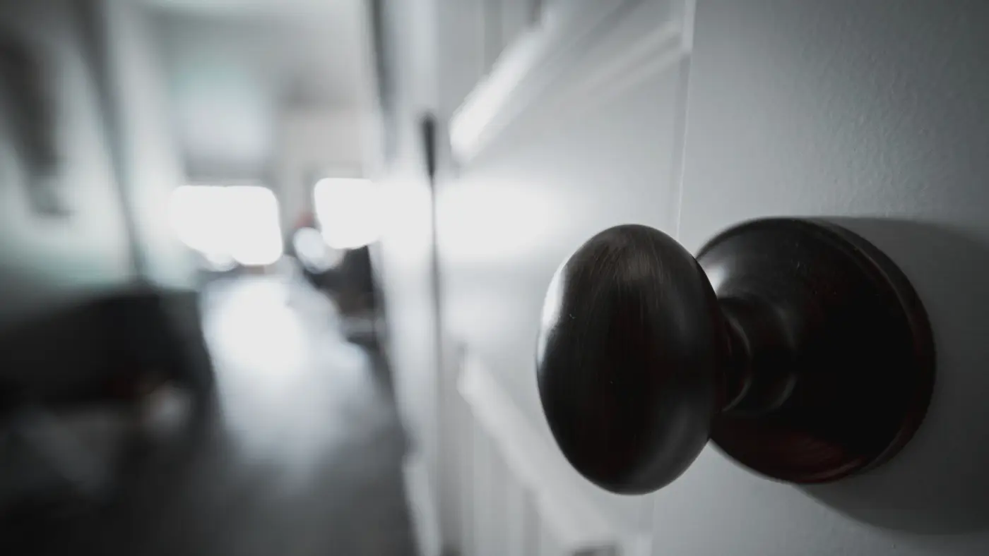 Une porte entrouverte sur un couloir, poignée au premier plan : un dossier d'état des lieux décrit le logement, son étage et parfois son code d'entrée.
