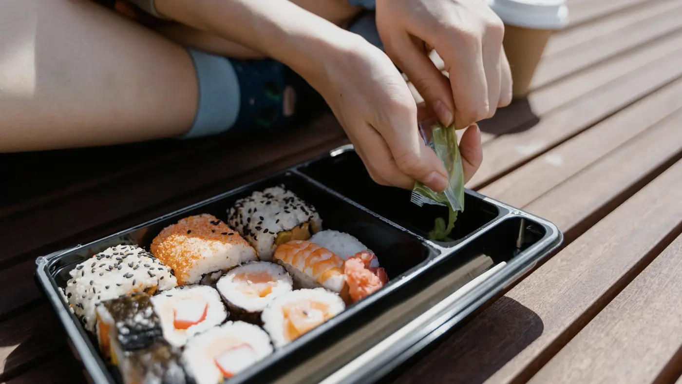 Une boîte de sushis à emporter posée sur une table en bois : chaque commande en ligne laisse un nom, un numéro et une adresse chez le restaurateur.