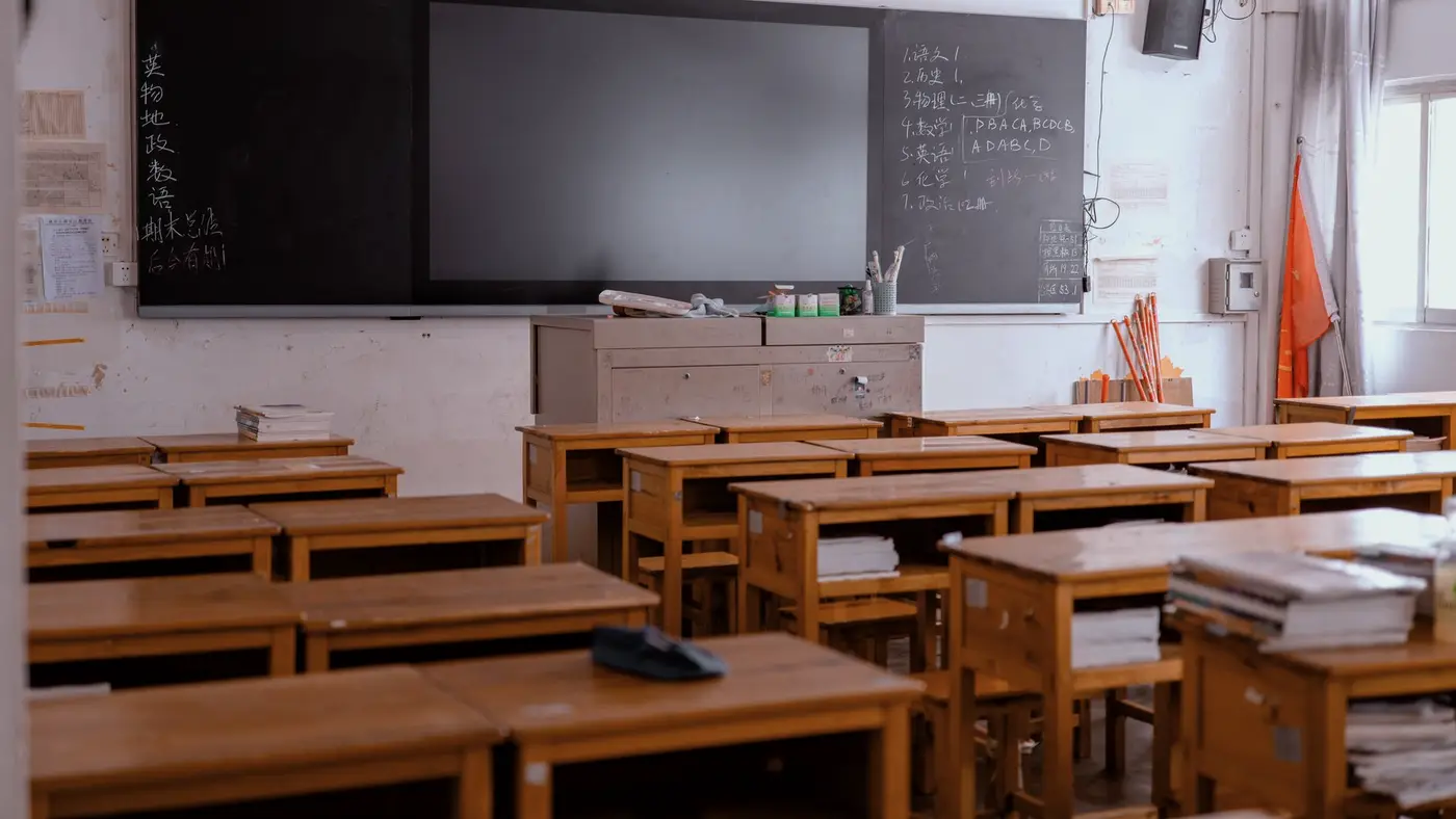 Une salle de classe vide où coexistent un tableau à craie et un écran éteint : la question de l'ordre dans lequel on outille l'enseignement.