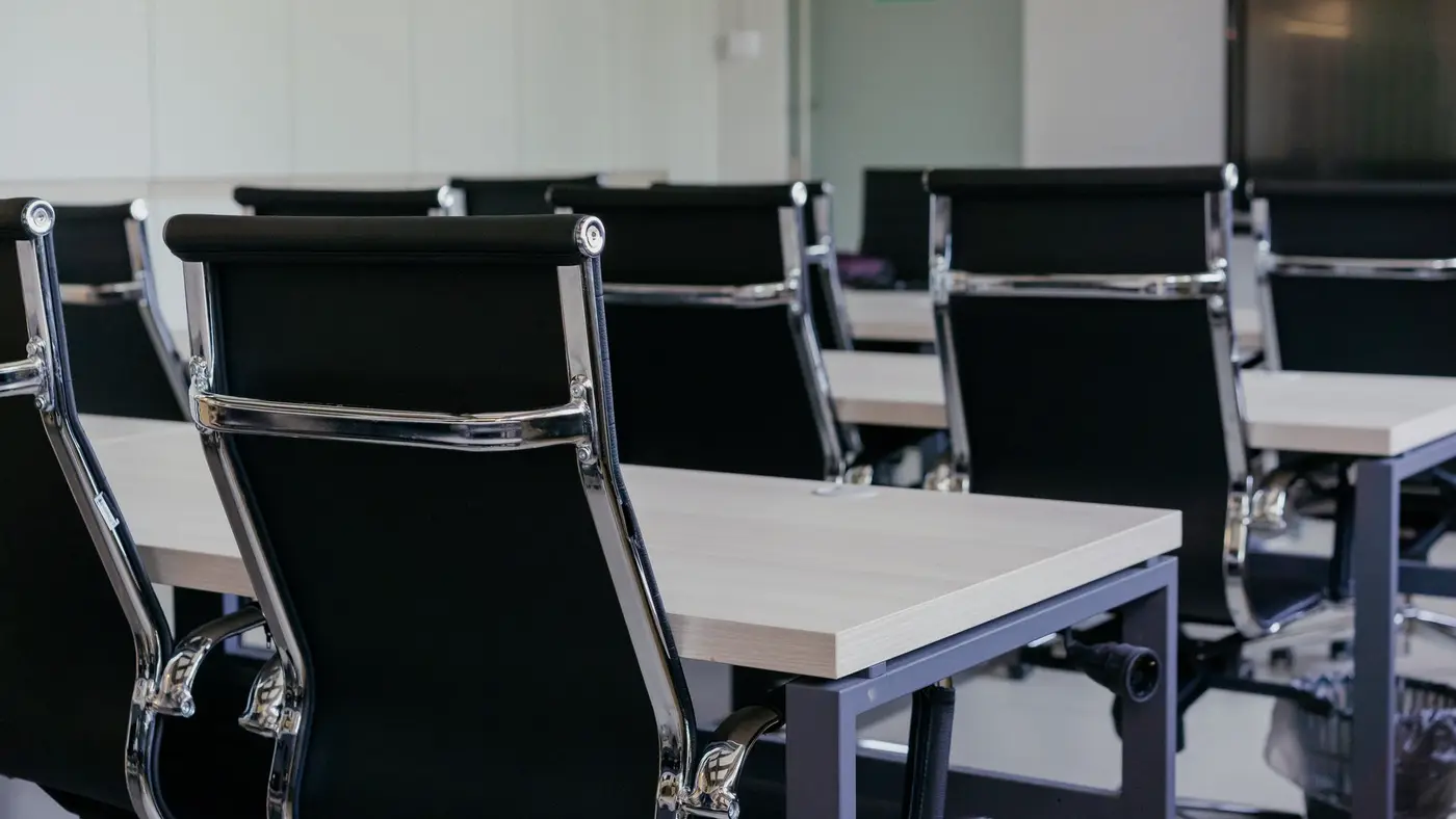 Des fauteuils vides alignés devant des bureaux : quand candidatures et tri passent par l'IA, la relecture humaine reste l'étape que le droit exige.