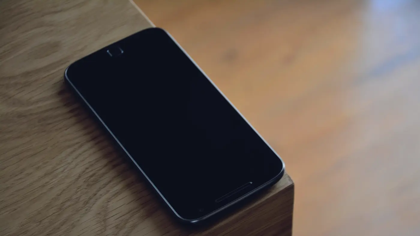 Un téléphone posé sur une table en bois : le message reçu ce matin-là ne dit pas d'où il vient.