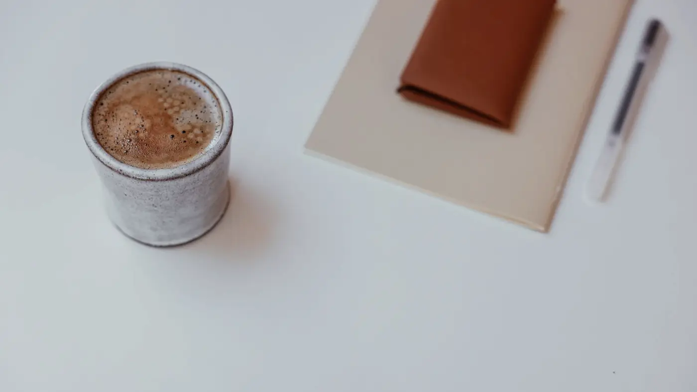 Une tasse de café et un carnet ouvert sur un bureau au petit matin, image d une revue d actualité quotidienne.