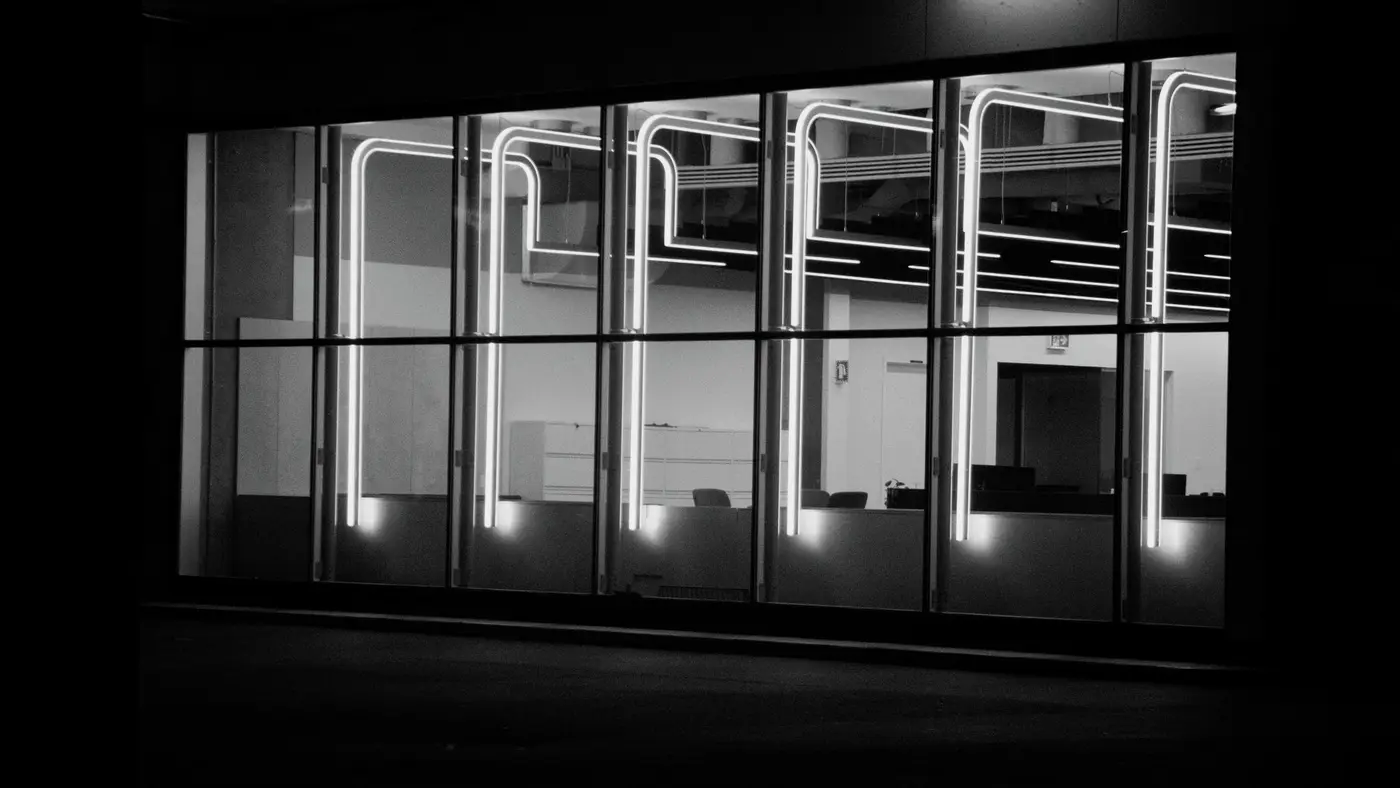 Un open space vide de nuit devant une ville éclairée, évoquant une actualité mondiale de l IA qui se joue pendant la nuit européenne.