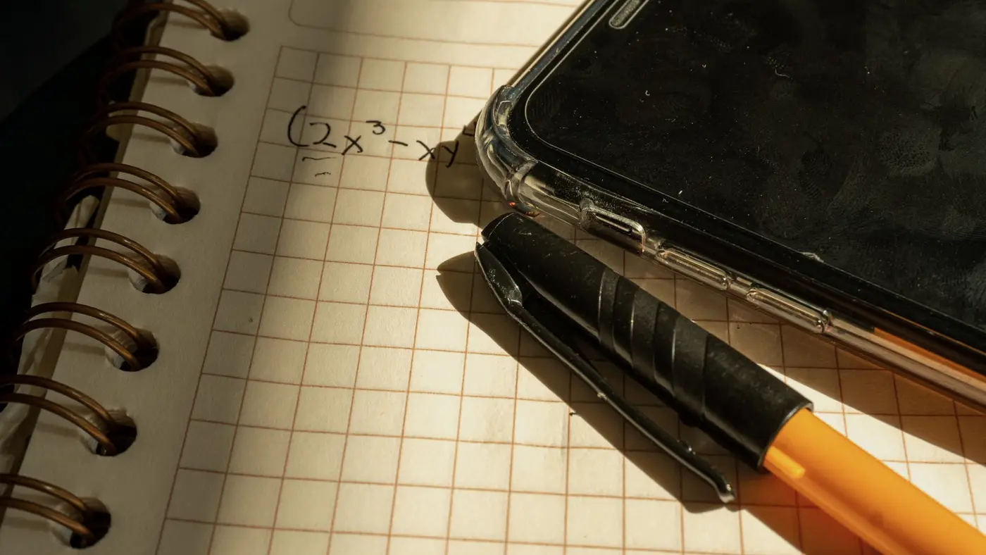 Un téléphone et un stylo posés sur un cahier d'écolier ouvert : ce que les jeunes doivent apprendre des outils qu'ils ont en poche.